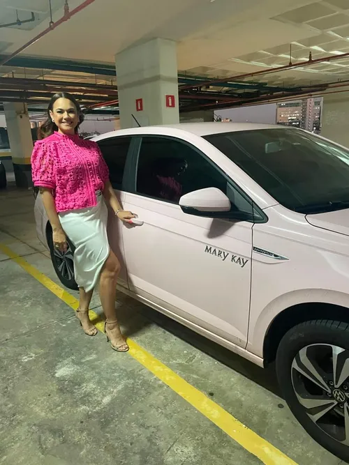 Consultora da equipe ao lado do carro Mary Kay